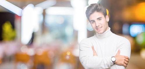 Fototapeta na wymiar Young handsome man wearing turtleneck sweater over isolated background happy face smiling with crossed arms looking at the camera. Positive person.