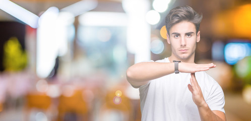 Young handsome man wearing white t-shirt over isolated background Doing time out gesture with...