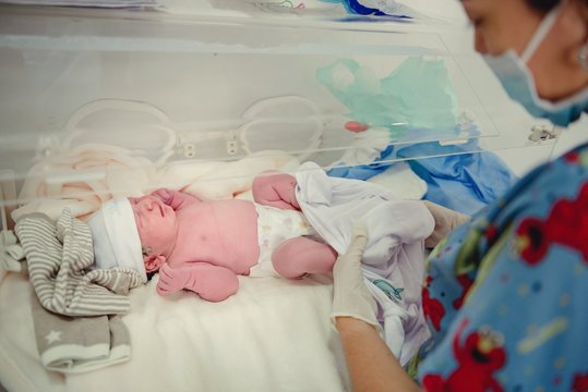 enfermera con bebe recién nacido sobre incubadora 