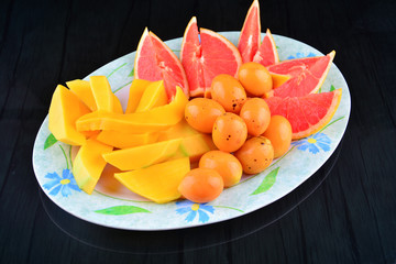 Fototapeta na wymiar Close Up of Bouea oppositifolia, grapefruits and mango on black background