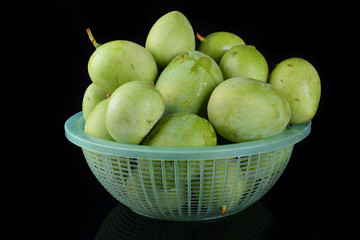 Fresh green mango in basket over black background