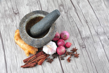 Mortar, star anise, cinnamon, ginger on a wooden background