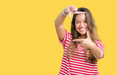 Obraz na płótnie Canvas Young beautiful brunette woman wearing stripes t-shirt over isolated background smiling making frame with hands and fingers with happy face. Creativity and photography concept.