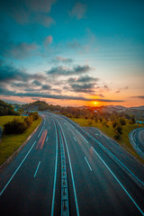 Sunset on a road, enter the clouds to cover the sun and take an orange color. Vertical photo, Basque Country © unai