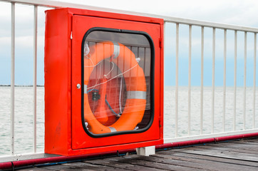 Life buoy in the showcase  hanging on a pontoon  bridge railing  at seashore . Tools to save people in case of emergency .