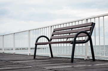 Close-up of  empty  wood sitting  bench on a  pontoon bridge      at seashore.  Concept of loneliness and contemplation .