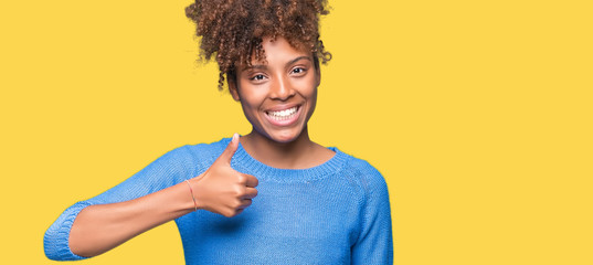 Beautiful young african american woman over isolated background doing happy thumbs up gesture with...