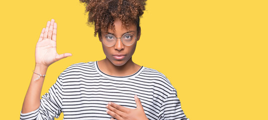 Beautiful young african american woman wearing glasses over isolated background Swearing with hand...