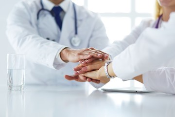 Team of doctors putting hands together, closeup