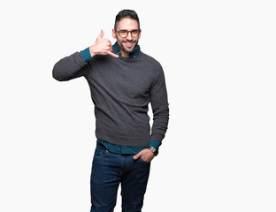 Naklejka premium Young handsome man wearing glasses over isolated background smiling doing phone gesture with hand and fingers like talking on the telephone. Communicating concepts.