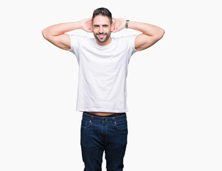 Handsome man wearing white t-shirt over white isolated background Relaxing and stretching with arms and hands behind head and neck, smiling happy