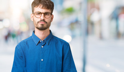 Young handsome man wearing glasses over isolated background skeptic and nervous, frowning upset because of problem. Negative person.