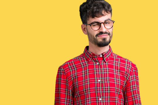 Young handsome man wearing glasses over isolated background winking looking at the camera with sexy expression, cheerful and happy face.