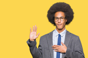 Young african american business man with afro hair wearing glasses Swearing with hand on chest and...