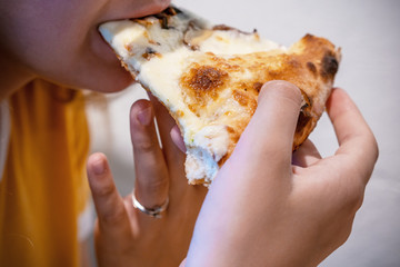 Cute little boy eats big bite of  pizza at a restaurant