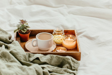 White bedding with dressing gown. Tray of coffee and candles. Breakfast in bed.  Scandinavian style.  Flat lay, top view