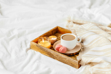 Obraz na płótnie Canvas Tray of coffee and candles with warm plaid on white bedding . Breakfast in bed. Scandinavian style. Flat lay, top view