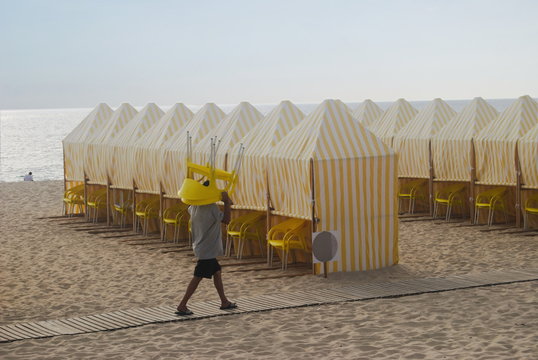 Trabalhador a arrumar cadeiras na praia ao por-do-sol