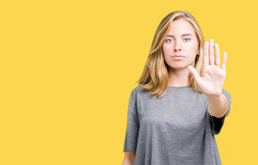 Beautiful young woman wearing oversize casual t-shirt over isolated background doing stop sing with palm of the hand. Warning expression with negative and serious gesture on the face.