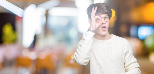 Young handsome man wearing glasses over isolated background doing ok gesture shocked with surprised face, eye looking through fingers. Unbelieving expression. © Krakenimages.com