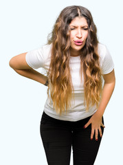 Young beautiful woman wearing casual white t-shirt Suffering of backache, touching back with hand, muscular pain