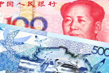 A red, one hundred yuan note from the People's Republic of China paired with a blue, five hundred tenge bank note from Kazakhstan