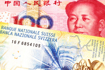 A yellow, ten Swiss franc note with a red, one hundred yuan renminbi bank note from the People's Republic of China