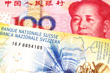 Fototapeta premium A yellow, ten Swiss franc note with a red, one hundred yuan renminbi bank note from the People's Republic of China
