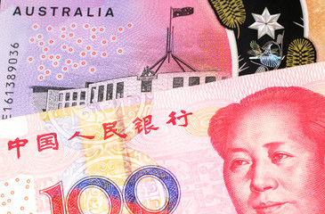 A close up image of a purple, five Australian dollar note close up, in macro with a red, one hundred yuan renminbi banknote from the People's Republic of China