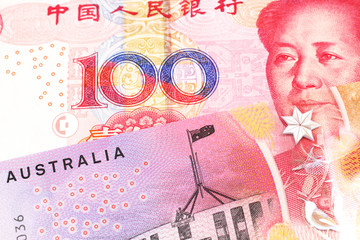 A close up image of a purple, five Australian dollar note close up, in macro with a red, one hundred yuan renminbi banknote from the People's Republic of China