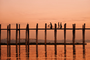 Unidentified people walk on U Bein bridge at sunset in Myanmar.