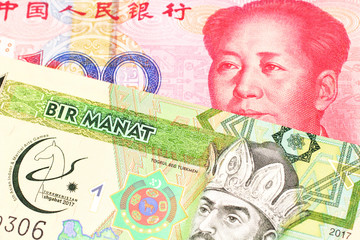 A green one manat note from Turkmenistan close up in macro with a red, one hundred yuan renminbi bank note from the People's Republic of China