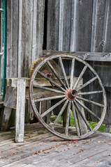 Fototapeta na wymiar Old wagon wheel and grindstone outside blacksmith shop