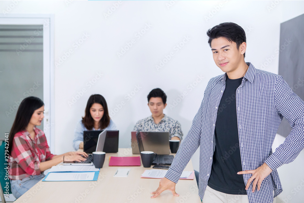 Wall mural Handsome entrepreneur stands with his team