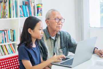 Girl uses laptop computer with grandfather