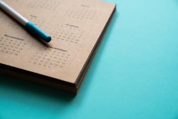 close up of calendar and pen on the green table background, planning for business meeting or travel planning concept