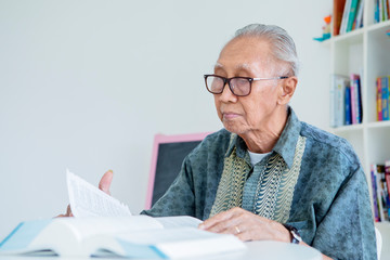 Senior man reading books on table in library