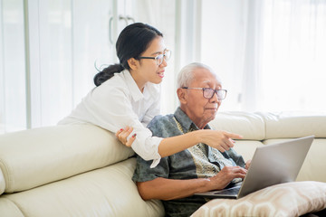Woman teaching senior man to use a laptop