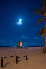 Midnight beach scene with full moon over ocean