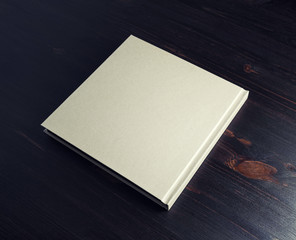 Photo of blank hardcover book on dark wooden background.