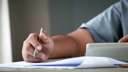 Education test exam in school concept : University student holding pen notes paper document sheet at lecture chair for taking exams in examination classroom. Assessment learning in class ideas