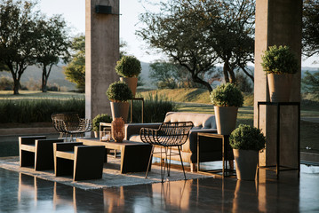 Armchairs and garden table adorned with pots, flowers and imitation leather fabrics.	