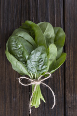 bunch of fresh spinach leaves on a wooden table. Vertical orientation. Healthy tasty vegan food.