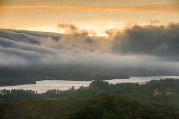 Fog Rolling over Crystal Springs Reservoir as seen from a vista point off Highway 280 on a Summer Sunset. Redwood City, San Mateo County, California, USA.