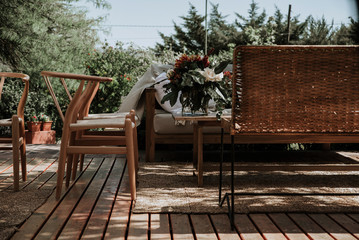 Wicker and steel tables and chairs decorated with vases with flowers of different colors.