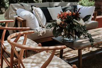 Wicker and steel tables and chairs decorated with vases with flowers of different colors.