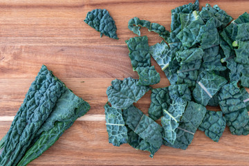 Bunch of dark green, crinkly, sliced Lacinato Kale leaves, on a wood cutting board