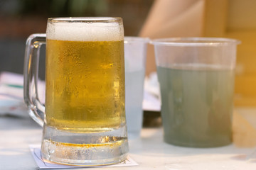 Close up of the cold glass beer with froth in pub & restaurant background.