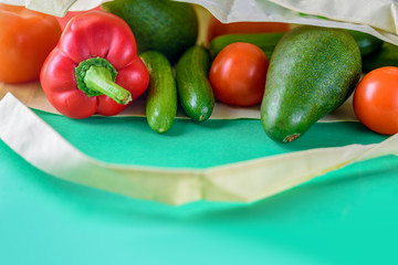 Plastic free shopping.Reusable eco friendly canvas grocery bag with red pepper, fresh tomatoes, cucumbers and avocado. Collection fresh vegetables. Farmers organic products. Less plastic.