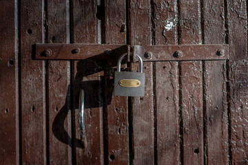 Old, brown gate with padlock.